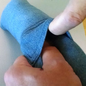 May include: A close-up of a blue denim fabric being pulled apart to reveal the inside of the fabric. The fabric is soft and has a subtle texture.