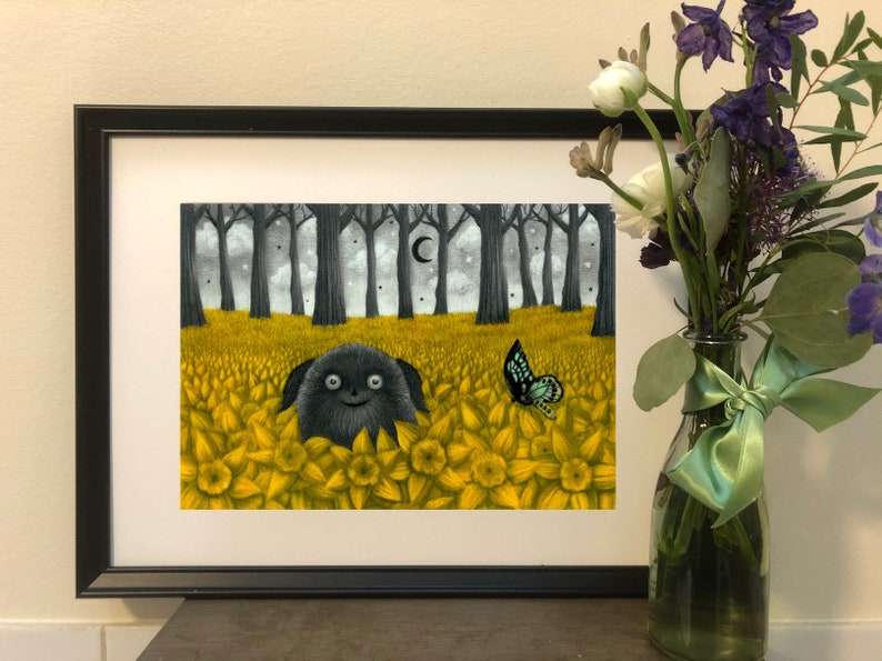 May include: A black and white illustration of a furry creature with a big smile, peeking out from a field of yellow flowers. A blue butterfly flies above the flowers. The background shows a dark forest with a crescent moon in the sky.