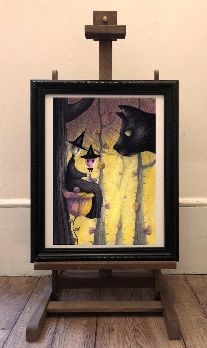 May include: A framed illustration of two witches sitting on a flower in a forest. The witches are wearing black robes and pointy hats. A black cat is looking at them from the right side of the image.