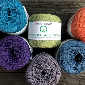 May include: Six balls of yarn in various colors, including teal, purple, gray, and blue. The yarn is labeled "HJERTE GARN ORGANIC 350 - WOOL COTTON 55% ORGANIC MERINO WOOL 45% ORGANIC COTTON".