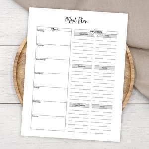 Op de afbeelding: Een printbare maaltijdplanner met een zwart-wit ontwerp. De linkerzijde is voor het opsommen van maaltijden voor elke dag van de week, en de rechterzijde is voor het opsommen van boodschappen om te kopen.