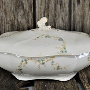 Side view of this beautiful casserole dish with the blue flowers and golden stems. Also showing the gold trim on the handles.