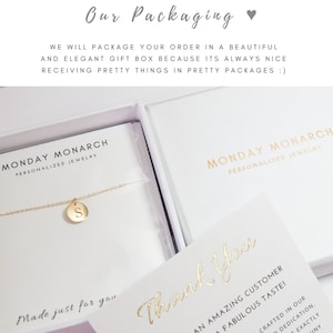 May include: A white gift box with a gold inscription that reads "Monday Monarch Personalized Jewelry". The box contains a gold necklace with a small gold pendant that has the letter "S" engraved on it. The box is sitting on a white surface. The text "Made just for you" is written in gold script on the box. A separate white card with the text "Thank You" written in gold script is also visible.