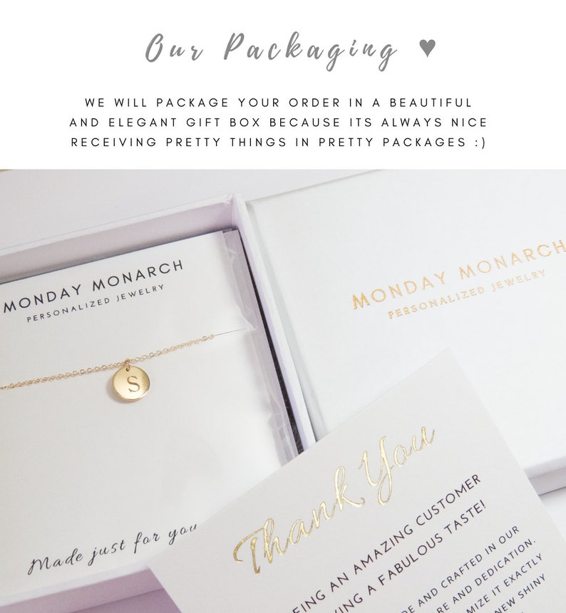May include: A white gift box with a gold inscription that reads "Monday Monarch Personalized Jewelry". The box contains a gold necklace with a small gold pendant that has the letter "S" engraved on it. The box is sitting on a white surface. The text "Made just for you" is written in gold script on the box. A separate white card with the text "Thank You" written in gold script is also visible.