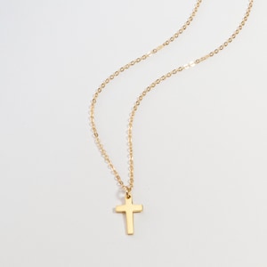 May include: A gold chain necklace with a small gold cross pendant.