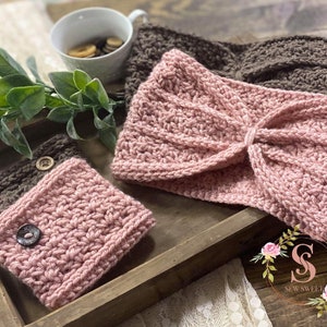 May include: Two crocheted headbands in brown and pink, and a pink crocheted wrist warmer with a button. The items are displayed on a wooden tray with a white lace doily and a floral design with the text "Sew Sweet".