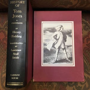 May include: A black hardcover book with gold lettering titled "The History of Tom Jones, A Foundling" by Henry Fielding, illustrated by Lawrence Beall Smith. The book is published by Random House.