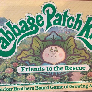 May include: A vintage Cabbage Patch Kids board game box. The box features the words "Cabbage Patch Kids" in green script, with an illustration of a Cabbage Patch Kid in a cabbage. The game is titled "Friends to the Rescue."