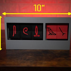 May include: A gray wooden box with a red and black design. The box is 10 inches wide, 5 inches tall, and 1.25 inches deep. The box has a hinged lid and is made of wood.