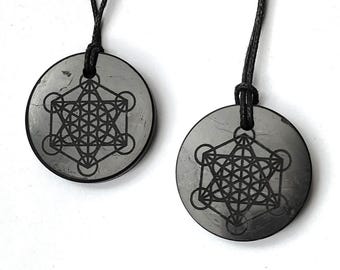 Può includere: Due ciondoli in ossidiana nera con un cordino nero. Ogni ciondolo presenta un design geometrico argentato, noto come Fiore della Vita.