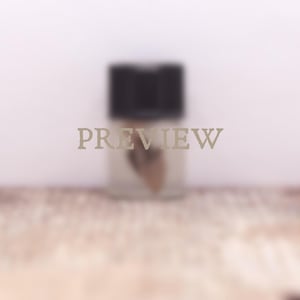 May include: A small, rectangular glass bottle with a black cap, featuring a blurred, light-colored liquid inside. The word PREVIEW is printed in a light, sans-serif font across the center of the bottle, partially obscuring the contents within.