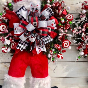 May include: A red and white Christmas wreath with a Santa Claus figure, a large black and white bow, and candy cane decorations.