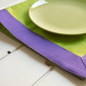 Op de afbeelding: Een groene en paarse placemat met een lichtgroen bord erop. De placemat heeft een brede paarse rand.