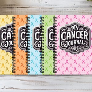 May include: A set of five spiral-bound journals featuring a repeating awareness ribbon pattern in yellow, orange, blue, green, and pink. Each cover displays a central metallic-style emblem with the text My Cancer Journal in bold lettering.