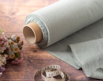 May include: A roll of light blue fabric with a brown cardboard core, a bouquet of dried flowers, and a white measuring tape with black markings on a wooden surface.