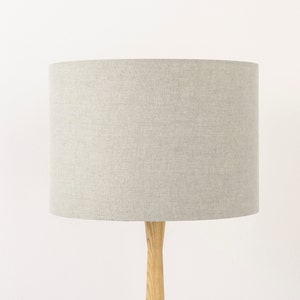 May include: A grey linen lampshade with a wooden base.