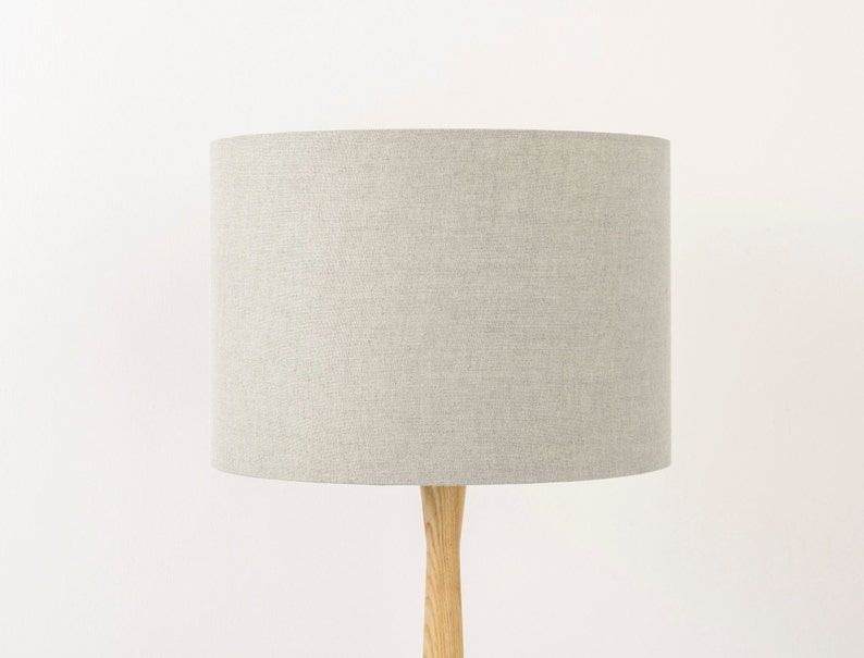 May include: A grey linen lampshade with a wooden base.