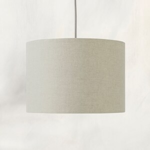 May include: A light beige drum-shaped lampshade with a linen texture.