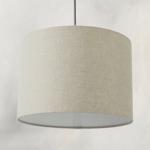 May include: A beige fabric drum pendant light shade with a white interior.