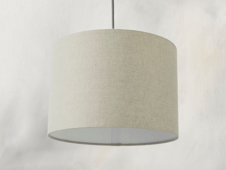 May include: A beige fabric drum pendant light shade with a white interior.