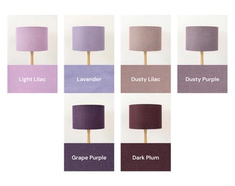 May include: A collection of six cylindrical fabric lampshades displayed in a grid, each featuring a different shade of purple. The colors are labeled as Light Lilac, Lavander, Dusty Lilac, Dusty Purple, Grape Purple, and Dark Plum.