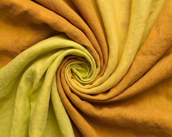 May include: A fabric textile featuring a spiral swirl pattern with a gradient colour transition from bright lemon yellow to deep golden orange. The material displays a visible woven texture with soft folds and drapes creating depth.