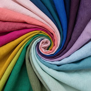 Puede incluir: Una colecci&oacute;n de muestras de tela dispuestas en un patr&oacute;n en espiral, con un espectro vibrante de colores que incluye amarillo mostaza, magenta, coral, rosa claro, azul profundo, verde azulado, morado, lavanda, azul claro y verde menta p&aacute;lido.