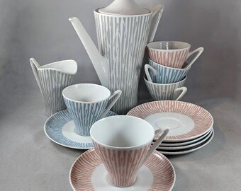 May include: A vintage coffee set with a gray and white striped teapot, creamer, and sugar bowl. The set includes four cups and saucers with a blue and white striped design and four cups and saucers with a pink and white striped design.