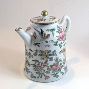 May include: White porcelain teapot with a lid and handle. The teapot is decorated with colourful floral and bird motifs. The spout and lid are trimmed with gold. The lid has a gold knob.