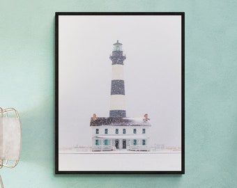May include: A black and white lighthouse with a white house in front of it. The lighthouse is tall and has a black and white striped design. The house is small and has a white roof. The scene is covered in snow.