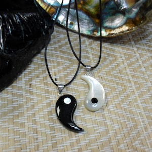 May include: Two yin yang pendants on black cords. One pendant is black with a white dot and the other is white with a black dot.