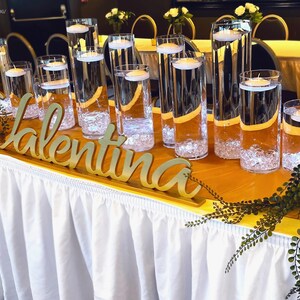 Personalized name sign in gold finish on long banquet table with champagne glasses, mis quince gift