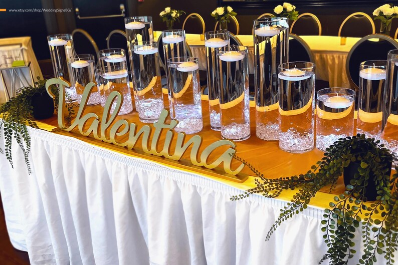 Personalized name sign in gold finish on long banquet table with champagne glasses, mis quince gift