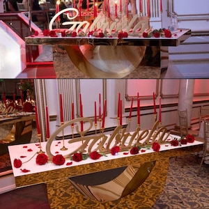 Custom wooden name sign in red glitter finish on decorated table, glamorous Quinceañera gift centerpiece
