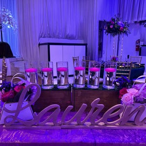 Personalized name sign in purple glitter finish at elegant Quinceañera party table, mis quince gift decor