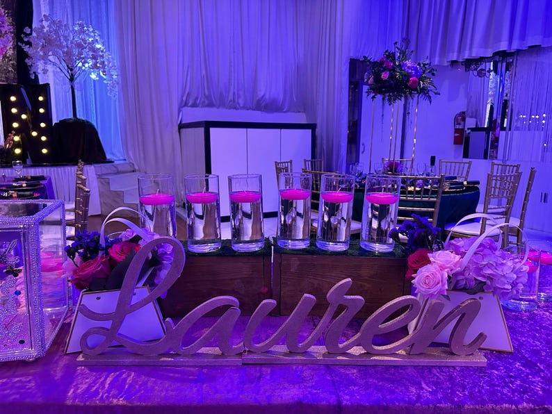 Personalized name sign in purple glitter finish at elegant Quinceañera party table, mis quince gift decor