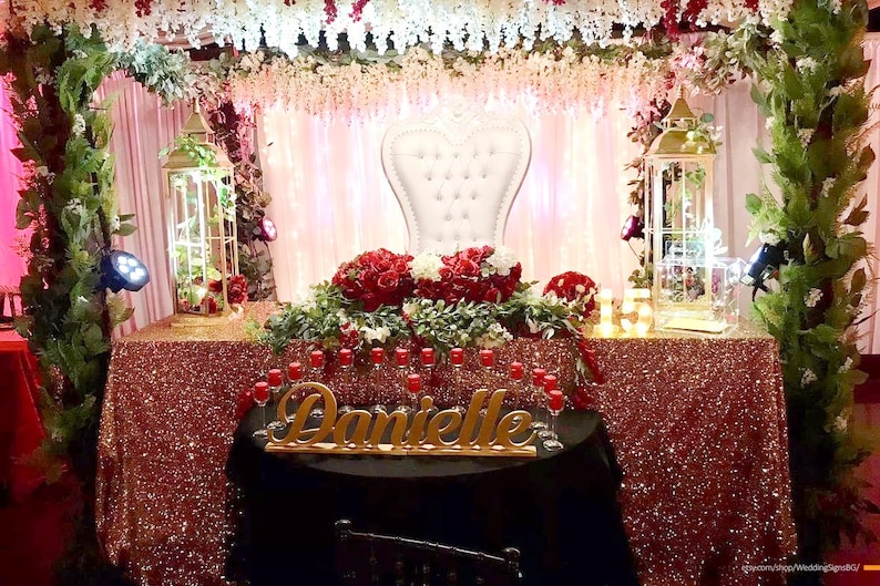 ustom wooden name sign at pink and red rose decorated Quinceañera sweetheart table centerpiece