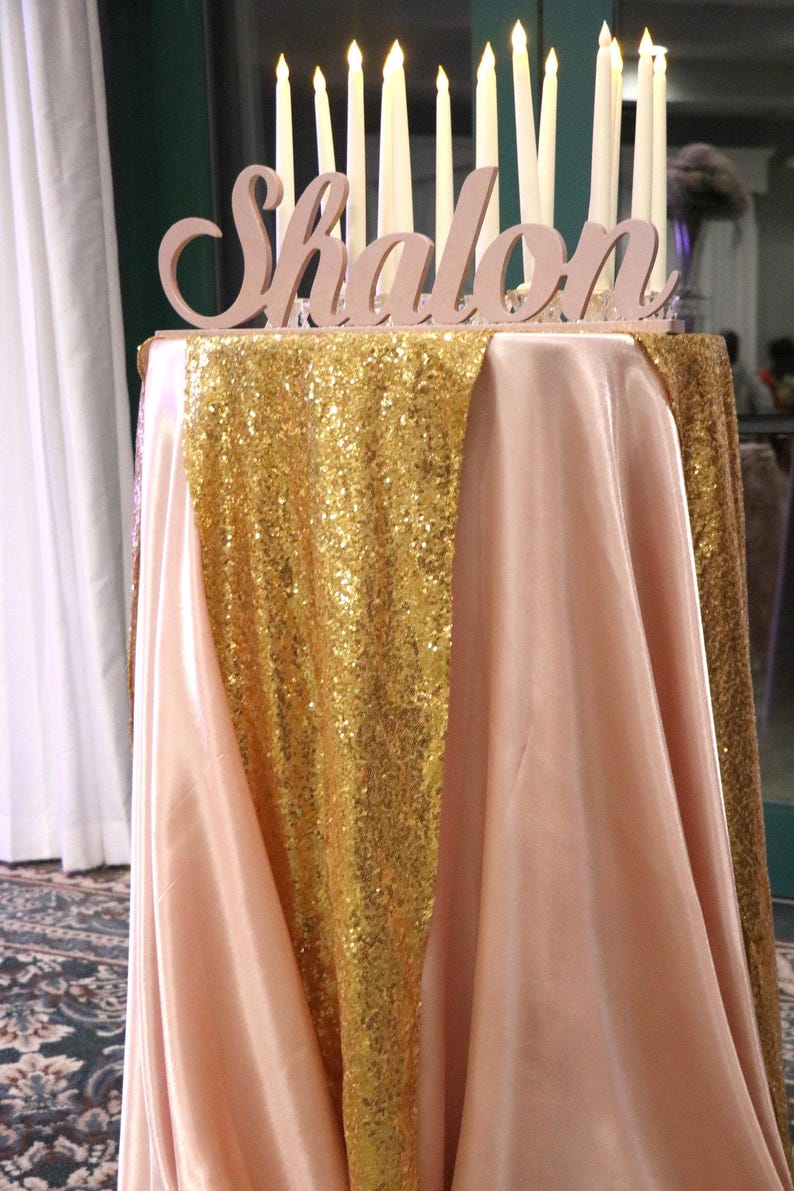 Custom wooden name sign in gold finish on sequin tablecloth, Quinceañera gift table centerpiece