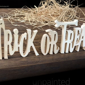 May include: Unpainted wooden sign that reads "Trick or Treat" in a whimsical font. The sign is made of individual letters and is perfect for Halloween decorations.