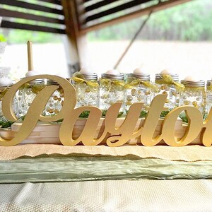 Multiple personalized name signs in gold finish displayed outdoors, garden party Quinceañera decor