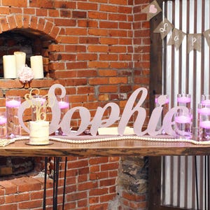 Large custom wooden name sign in rose gold finish on brick wall background, freestanding mis quince decor