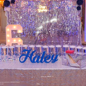 Custom wooden name sign in silver glitter finish on illuminated table, Quinceañera birthday gift decor