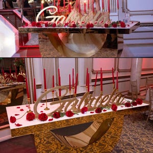 Personalized name sign in red glitter finish on decorated table, glamorous Quinceañera party centerpiece