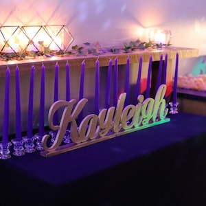 Custom wooden name sign in blue glitter finish on illuminated table, Quinceañera birthday centerpiece