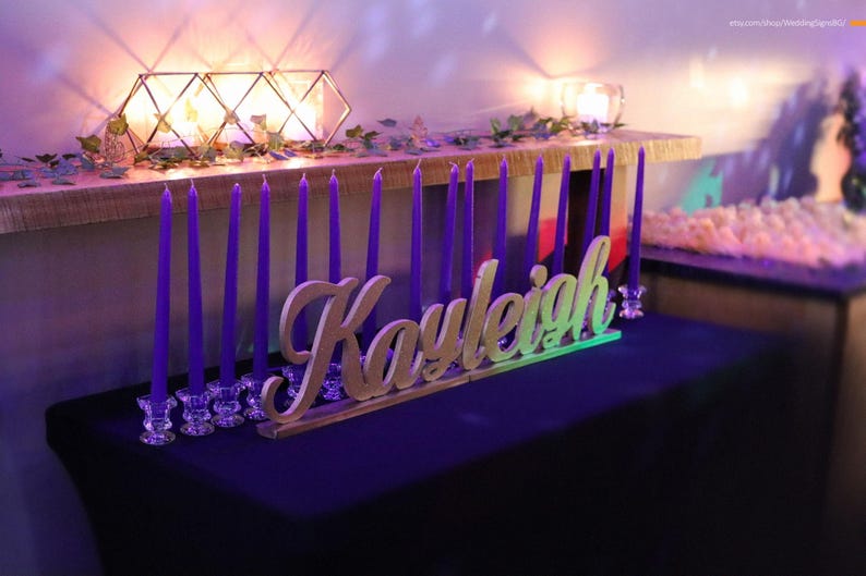 Custom wooden name sign in blue glitter finish on illuminated table, Quinceañera birthday centerpiece