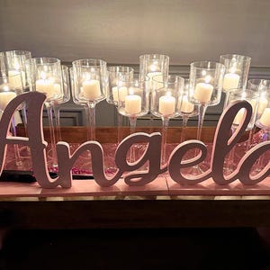 Custom wooden name sign in gold glitter finish with string lights, elegant Quinceañera centerpiece