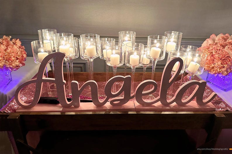 Custom wooden name sign in gold glitter finish with string lights, elegant Quinceañera centerpiece