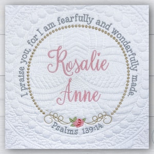 May include: White quilted fabric with a circular design featuring the text "I praise you, for I am fearfully and wonderfully made."  The names "Rosalie Anne" are embroidered in pink inside the circle. The text "Psalms 139:14" is also embroidered below the circle.