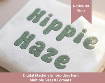 May include: A white fabric surface featuring sage green machine embroidery text that reads Hippie Haze. A pink banner in the upper right corner displays the text Native BX Font, and the bottom text reads Digital Machine Embroidery Font.