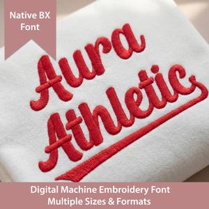 Op de afbeelding: Een wit stoffen oppervlak met rode, machinaal geborduurde tekst die Aura Athletic in cursief schrift weergeeft. Een roze banner linksboven toont de tekst Native BX Font en een roze banner onderaan toont Digital Machine Embroidery Font Multiple Sizes & Formats.